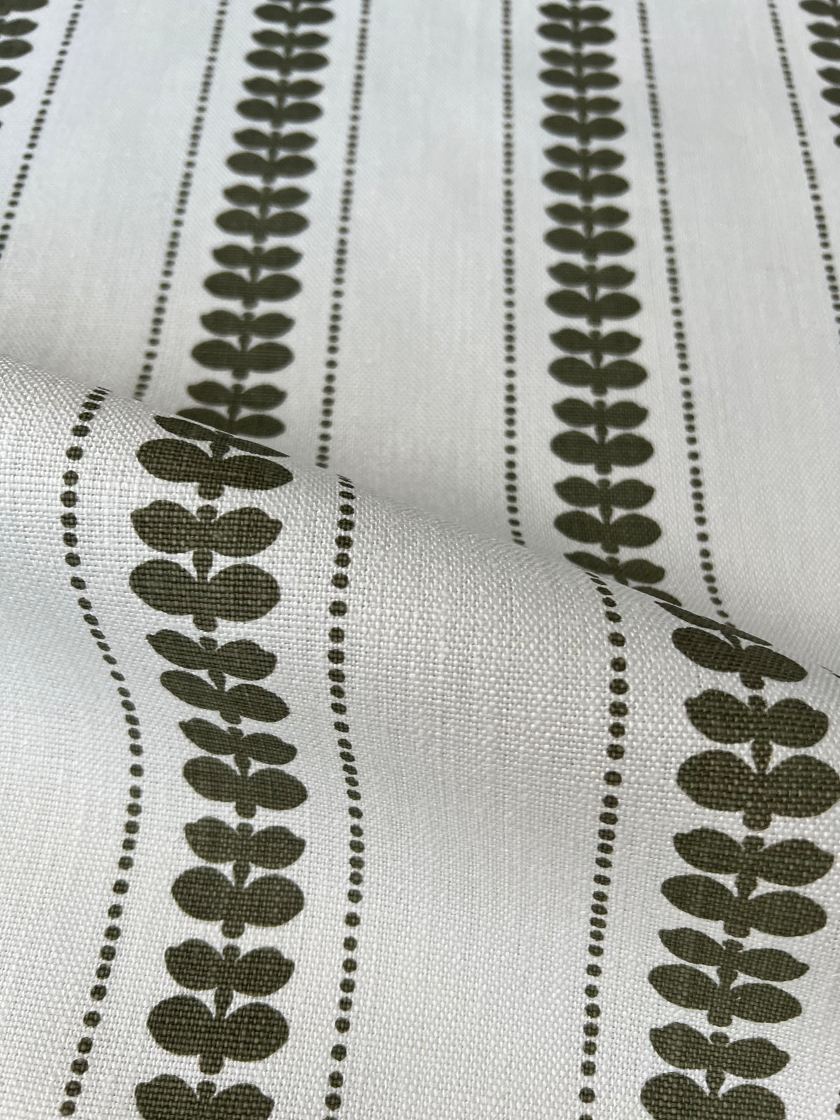 Artisan screen-printed linen with Elodie’s floral stripe design — delicate botanical elements arranged in a subtle, repeating rhythm. olive green on oyster. Hand-printed by artisans, Greige Textiles&#39; fabrics and wallpapers add a refined touch to any interior.