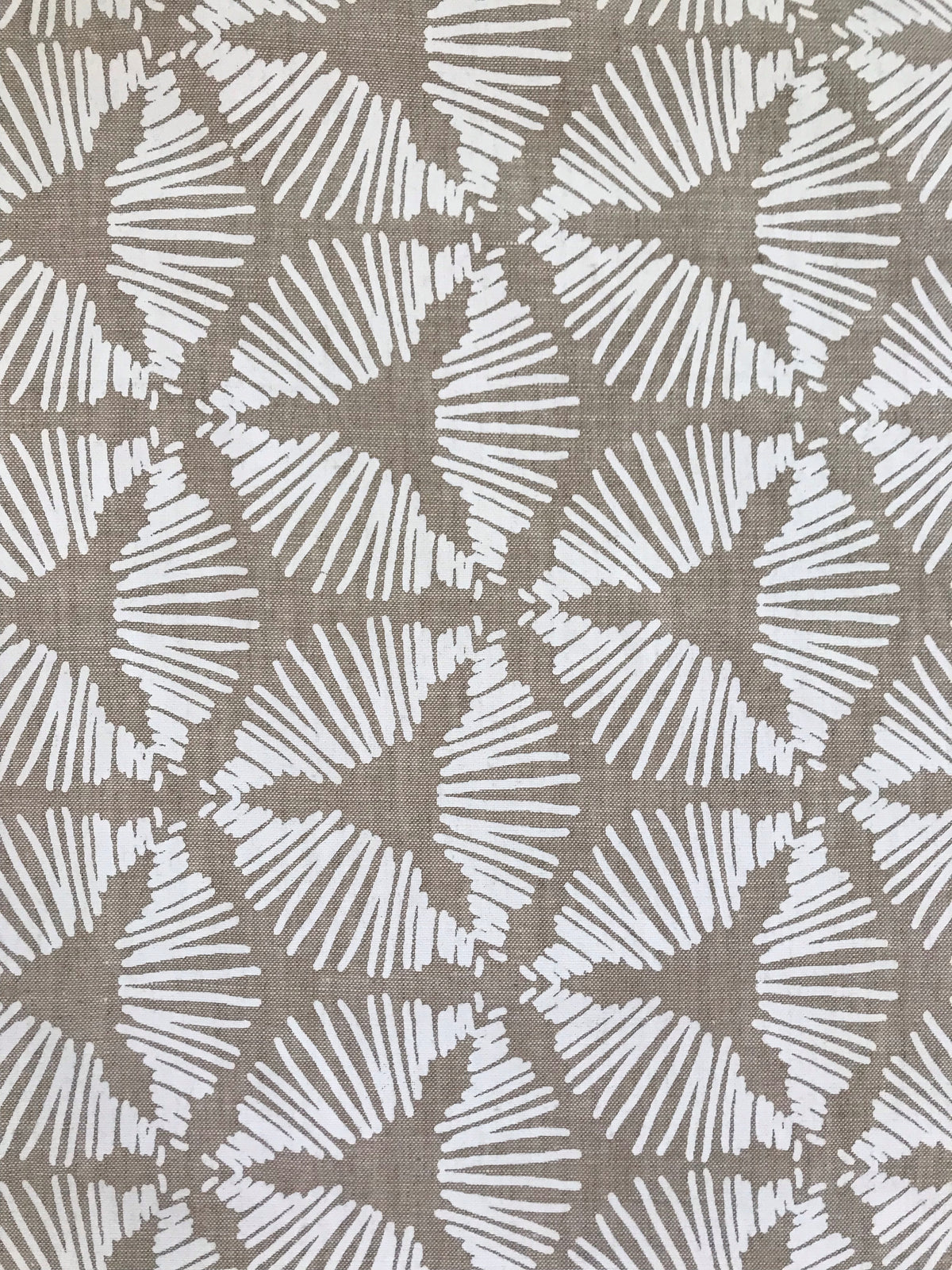 The Cie pattern radiates striking visual rhythm with its bold starburst shield design. A dynamic textile hand printed on Belgian linen, ideal for upholstery, cushions, and drapery in spaces that embrace graphic elegance.