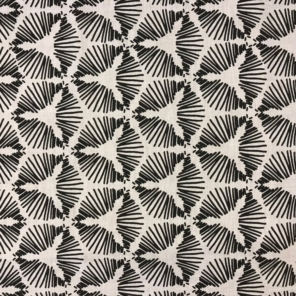 Cie by Greige Textiles — a dramatic starburst shield motif that brings graphic energy and sculptural movement to interiors. Hand printed on Belgian linen, it&#39;s a bold choice for drapery, statement cushions, or tailored upholstery.