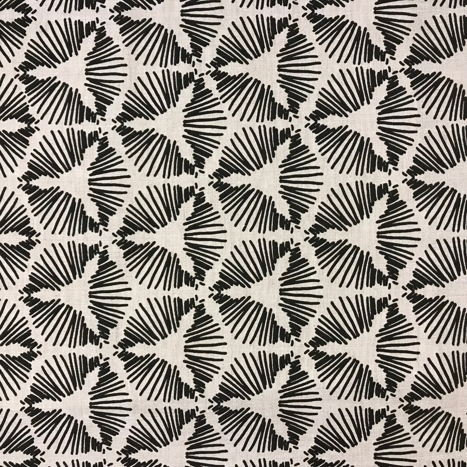 Cie by Greige Textiles — a dramatic starburst shield motif that brings graphic energy and sculptural movement to interiors. Hand printed on Belgian linen, it's a bold choice for drapery, statement cushions, or tailored upholstery.