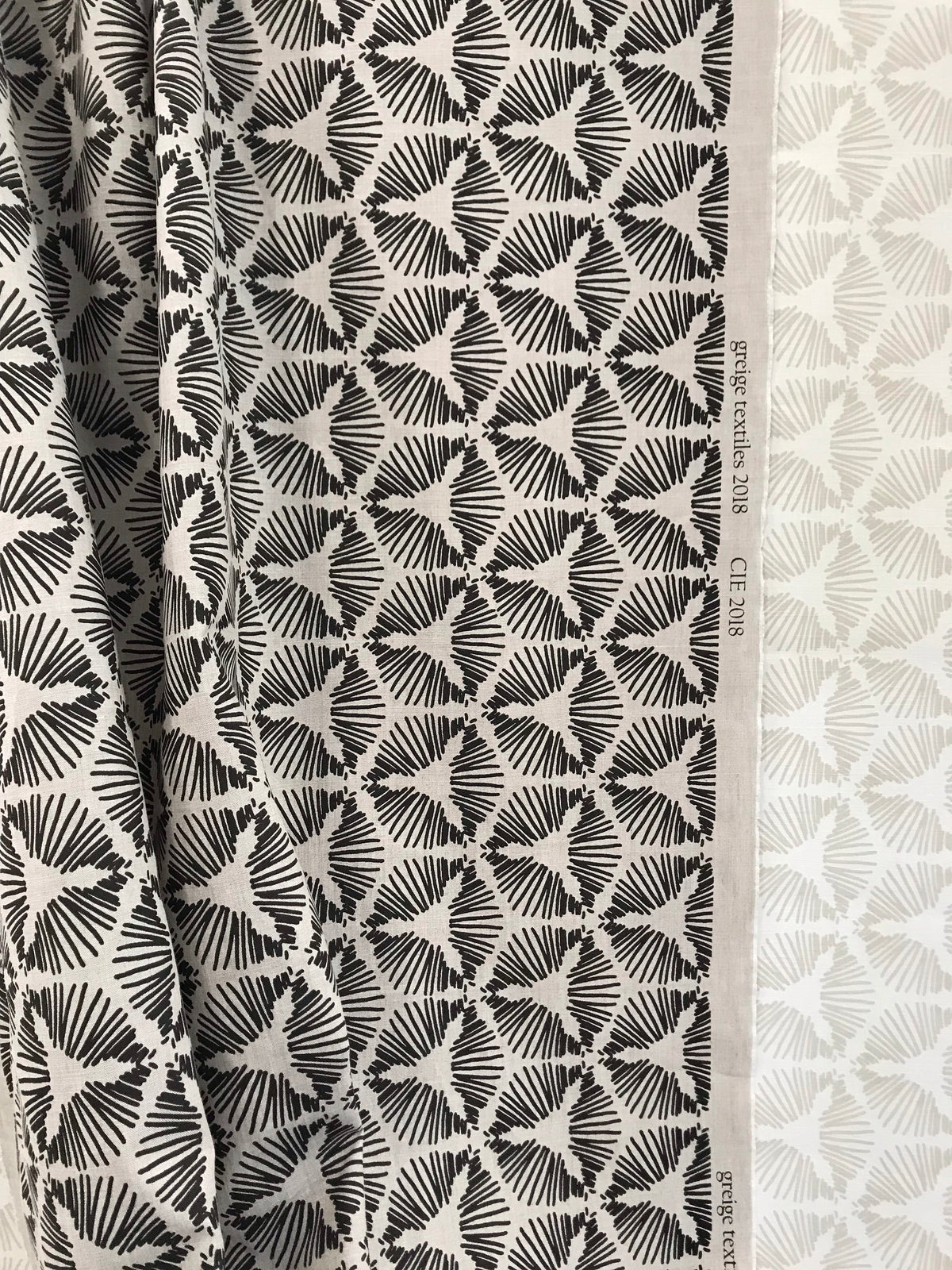 Cie by Greige Textiles — a dramatic starburst shield motif that brings graphic energy and sculptural movement to interiors. Hand printed on Belgian linen, it&#39;s a bold choice for drapery, statement cushions, or tailored upholstery.