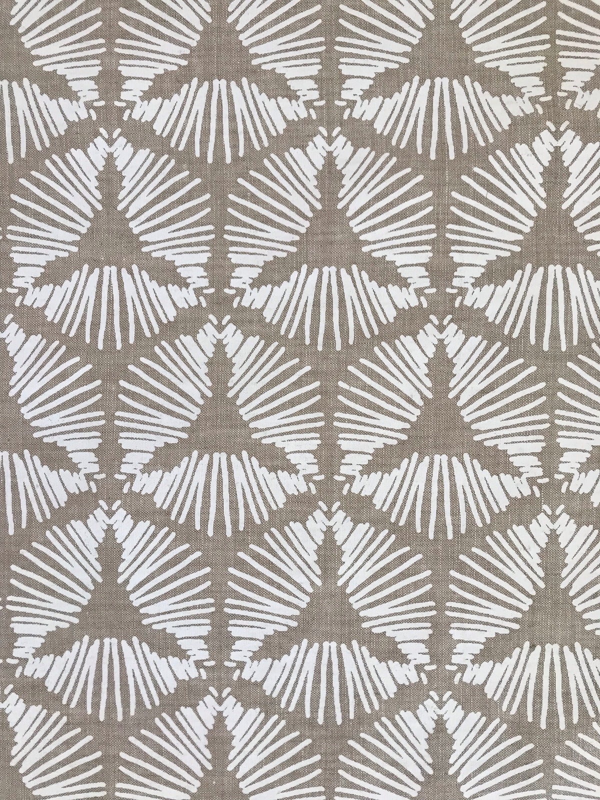 The Cie pattern radiates striking visual rhythm with its bold starburst shield design. A dynamic textile hand printed on Belgian linen, ideal for upholstery, cushions, and drapery in spaces that embrace graphic elegance.