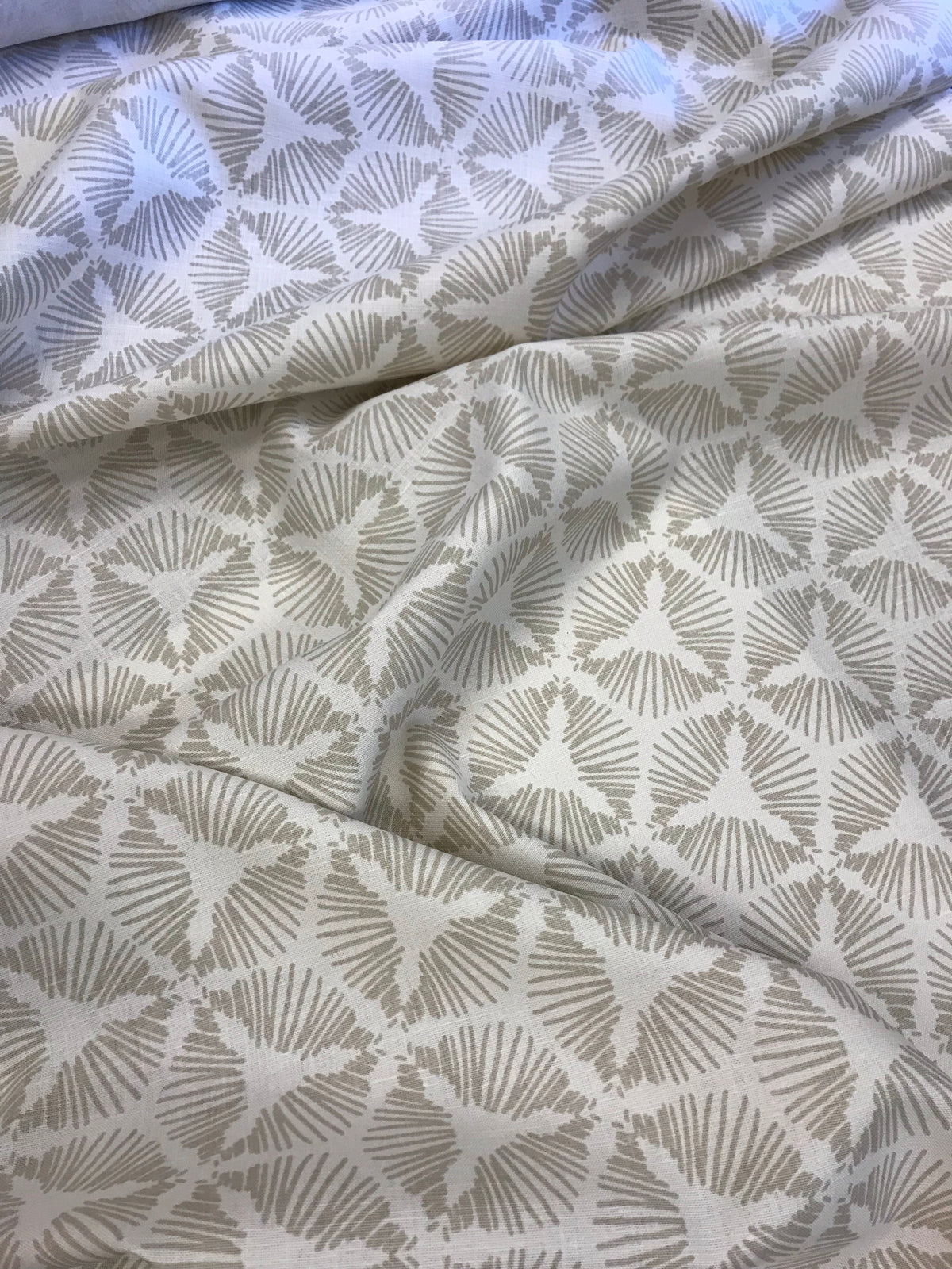 Cie by Greige Textiles channels bold movement and graphic drama in its radiant starburst shield pattern, hand printed on Belgian linen for statement-making design moments